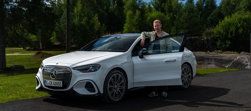 Ein Mann steht in der Tür einer weißen Mercedes C-Klasse Limousine.