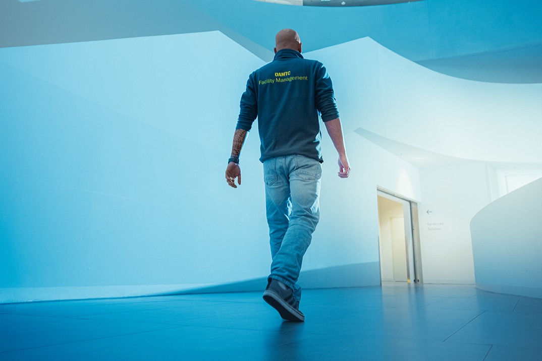 Auf dem Bild sieht man einen Mann von hinten der auf eine erleuchtete Tür in einer weißen Wand zugeht.