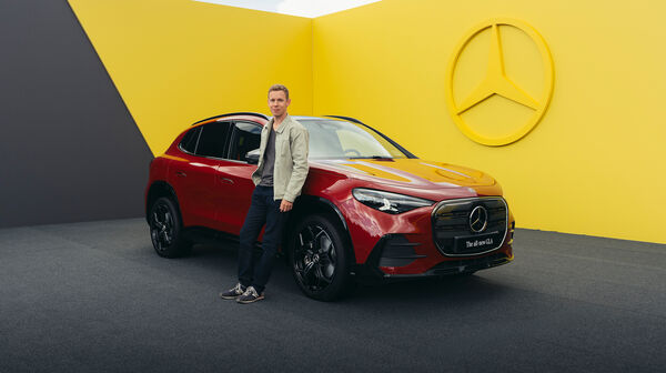 Ein Mann lehnt an einem roten Mercedes-SUV.