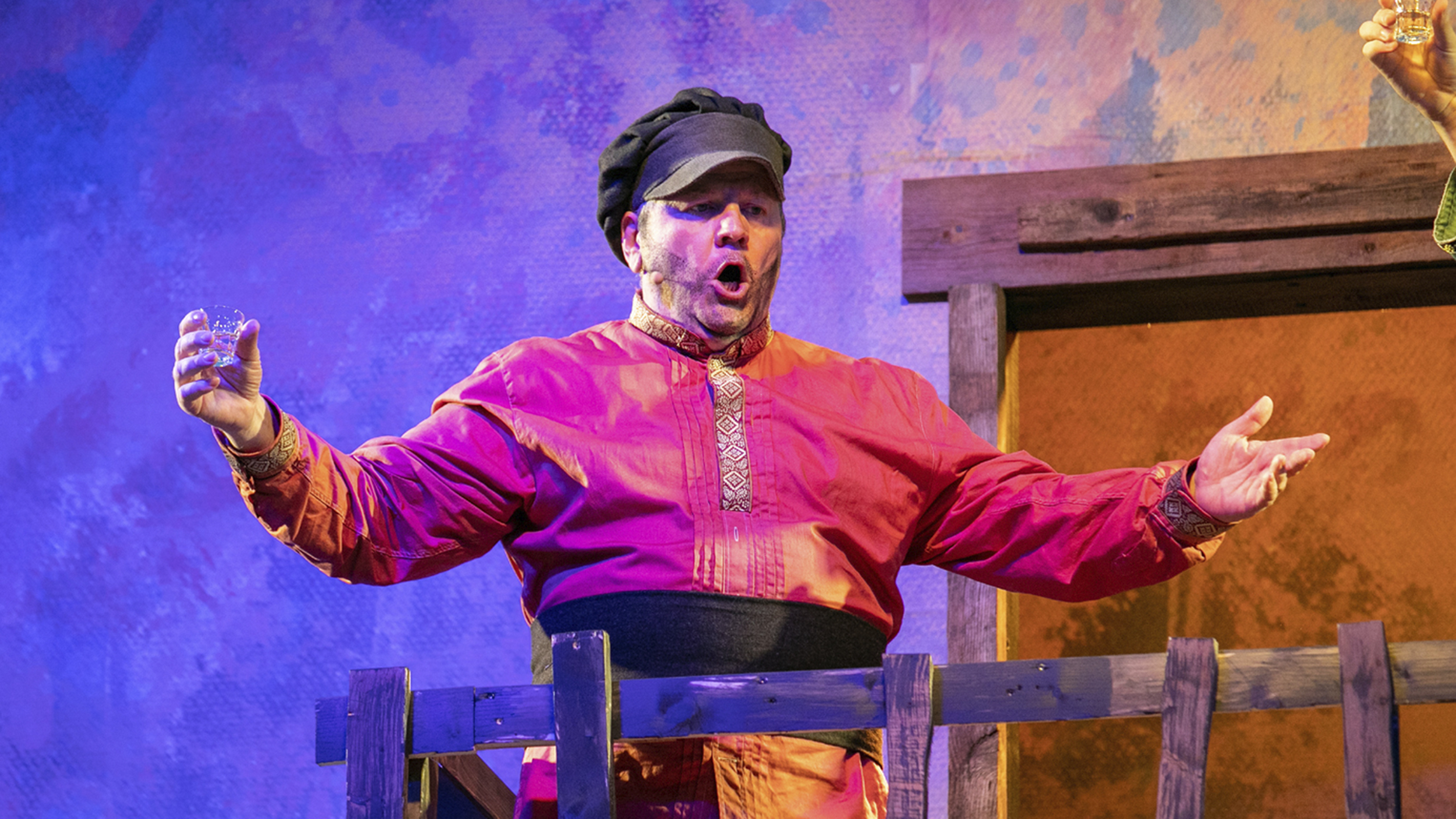 Ein Mann steht im roten Kostüm auf der Bühne im Musical Anatevka.