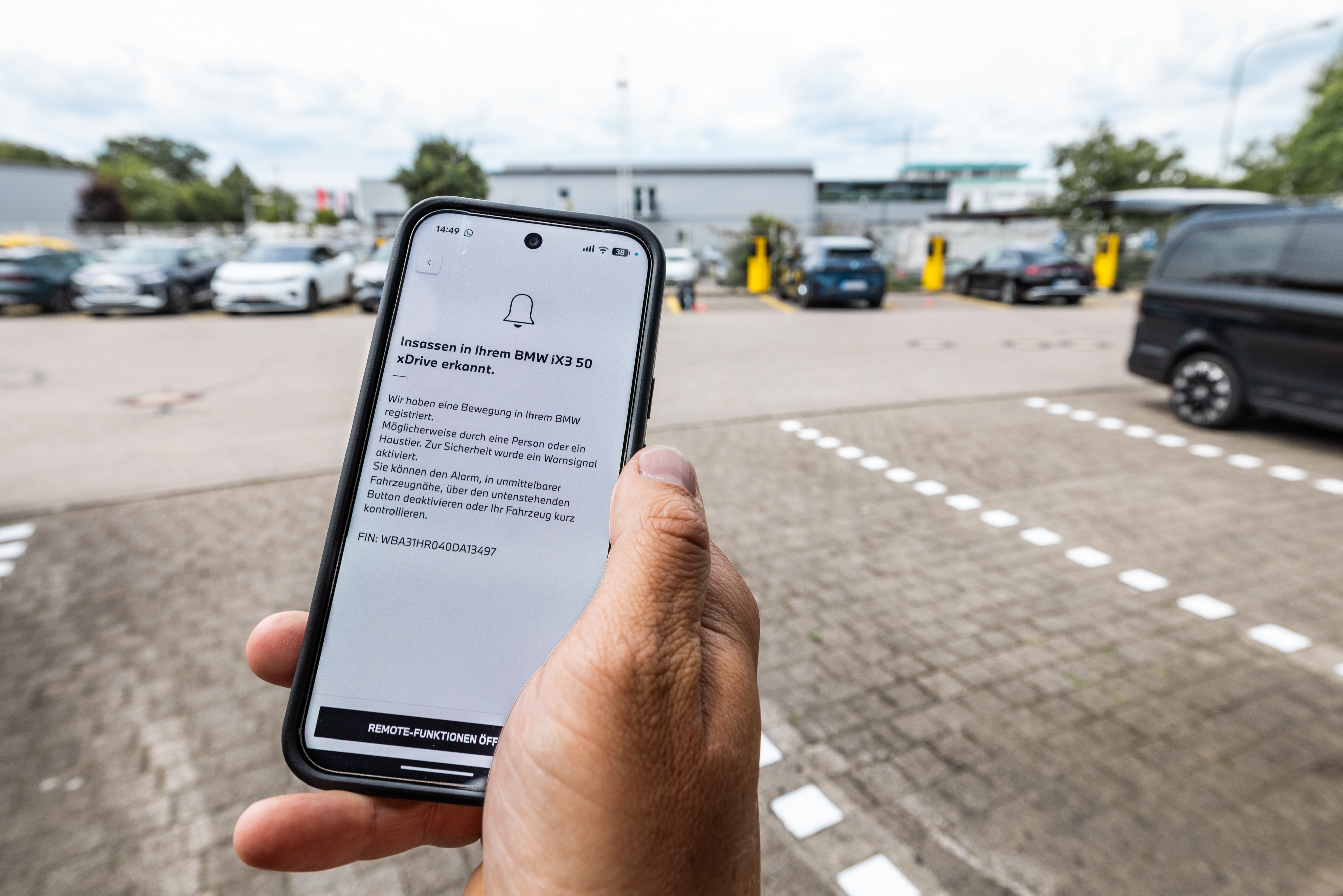 Man sieht ein Hand auf der eine Warnmeldung angezeigt wird, dass ein Insasse im Auto erkannt wurde.