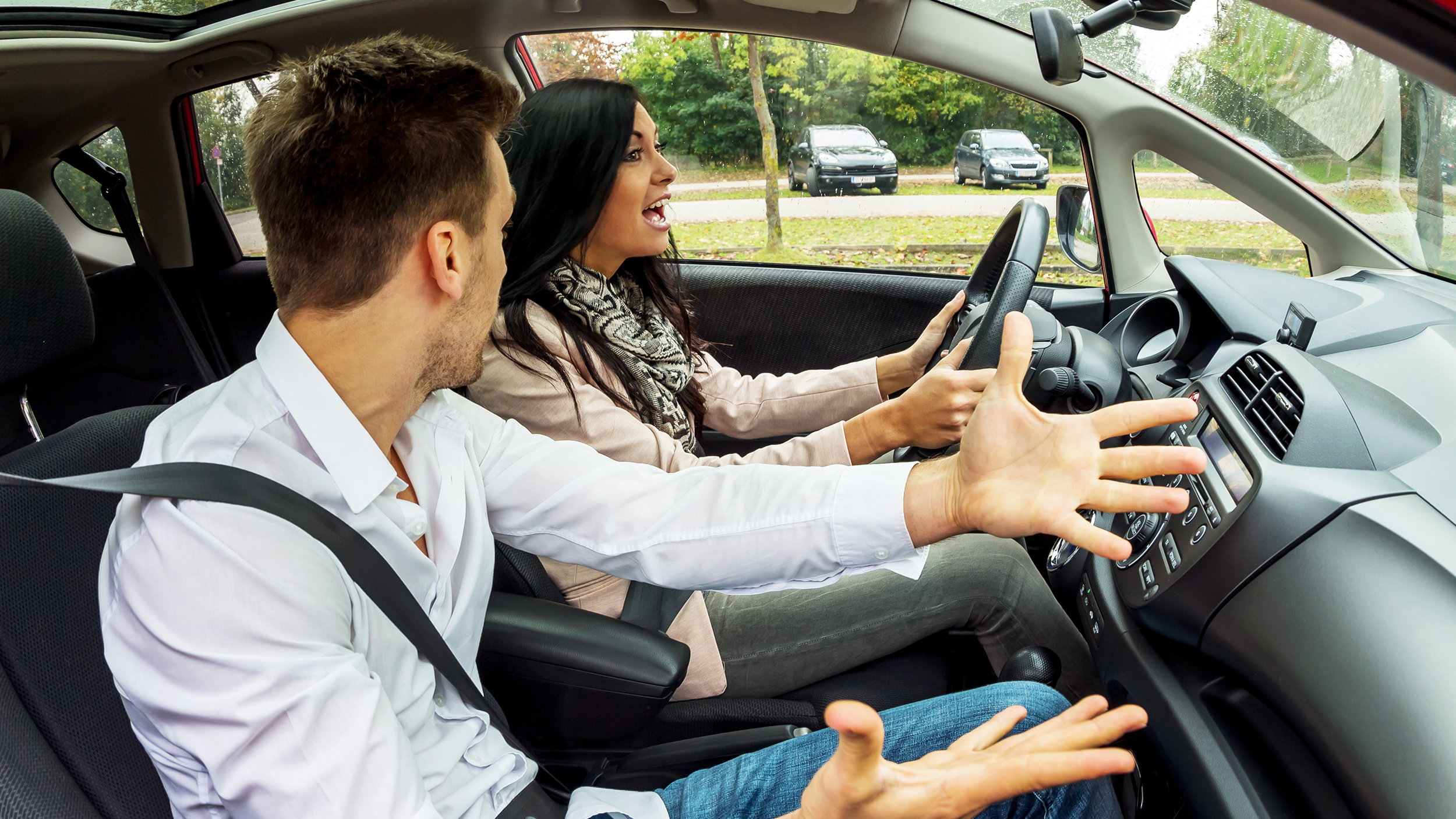 Ein Beifahrer und eine Fahrerin streiten sich im Auto.