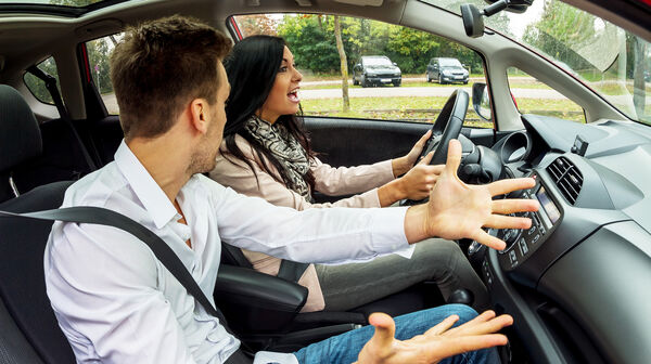 Ein Beifahrer und eine Fahrerin streiten sich im Auto.