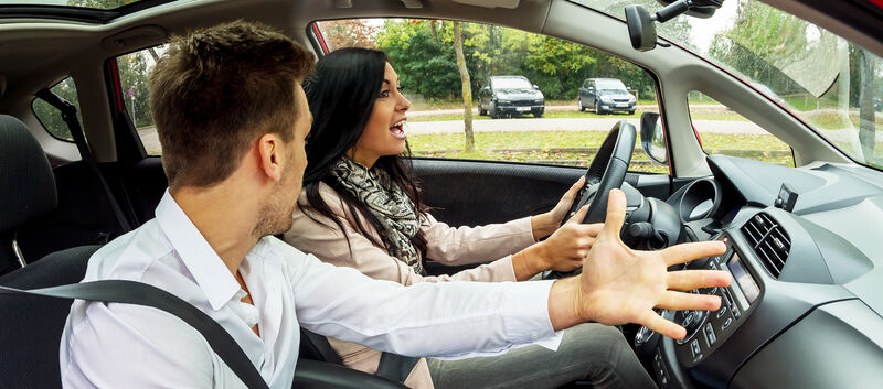 Ein Beifahrer und eine Fahrerin streiten sich im Auto.