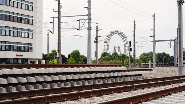 Zugschienen und Strecke, im Hintergrund ein Hochhaus und Stromleitungen.