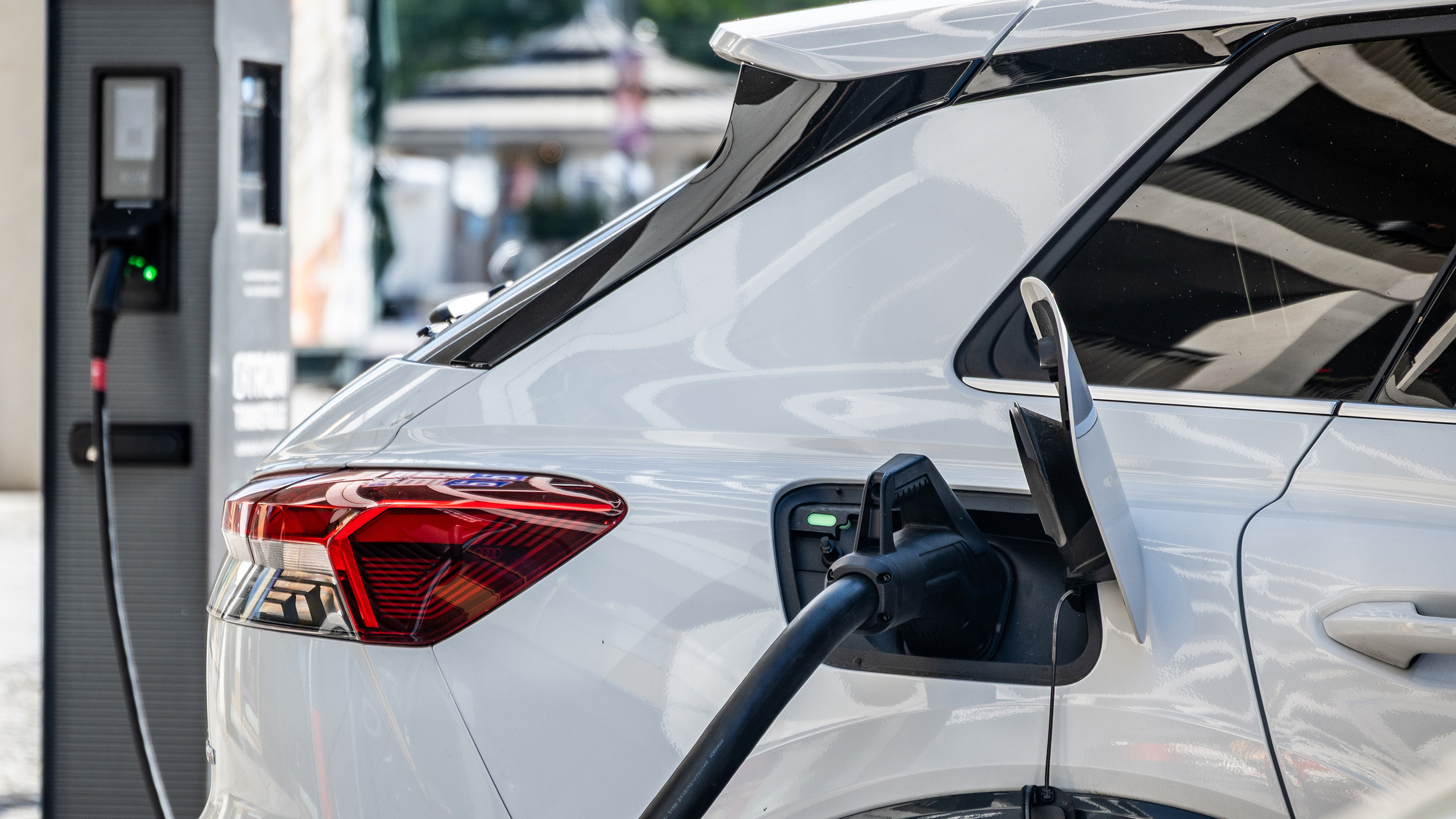 Ein weißes Elektroauto lädt an einer Ladesäule.