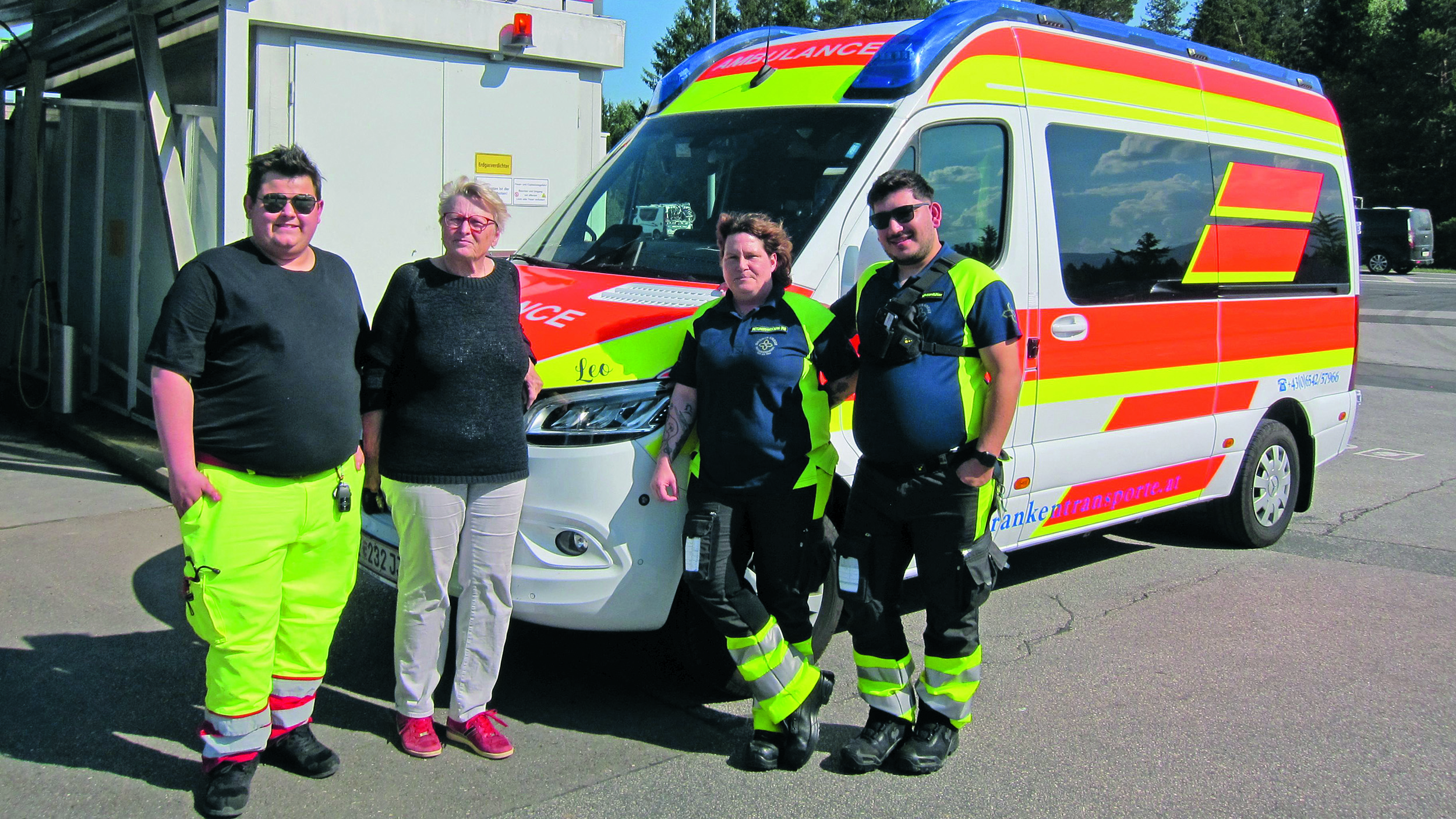 Ein ÖAMTC-Mitglied steht mit Sanitäter:innen vor einem Rettungsfahrzeug.