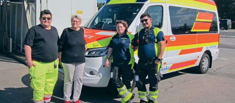 Ein ÖAMTC-Mitglied steht mit Sanitäter:innen vor einem Rettungsfahrzeug.
