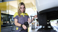 Jessica, ein junger Lehrling in Ausbildung zur Kfz-Technikerin misst den Reifendruck an einem Auto.