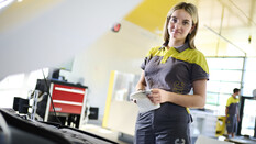 Jessica, ein junger Lehrling in Ausbildung zur Kfz-Technikerin steht vor geöffneter Motorhaube in der ÖAMTC-Werkstatt und kontrolliert den Ölpegel.