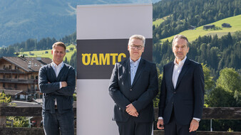 Drei Männer in Anzügen stehen vor einem ÖAMTC-Schild.