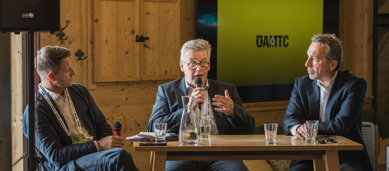 Drei Männer in Anzügen führen eine Diskussion