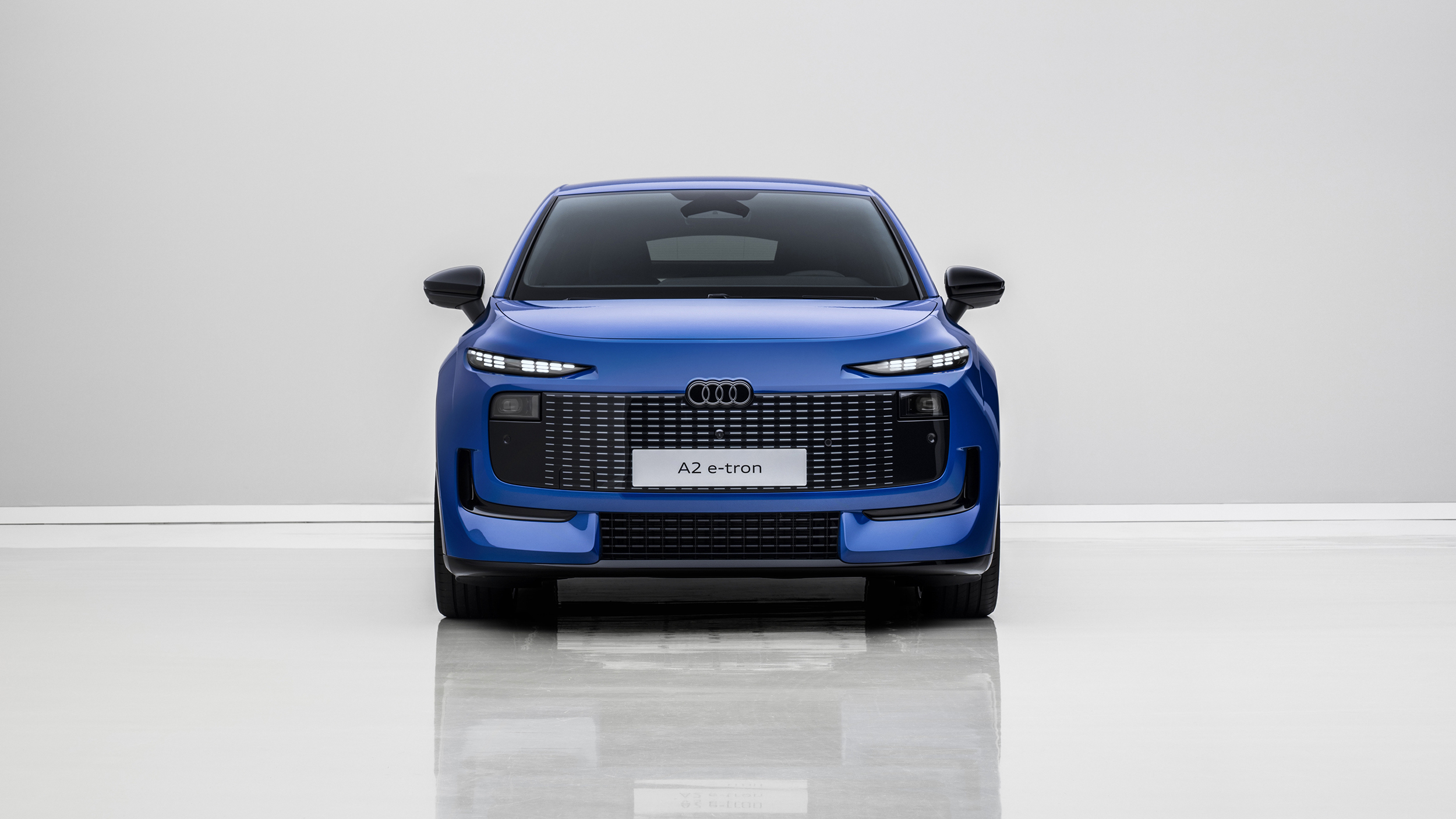 Front eines blauen Audi A2 e-tron, der in einem weißen Studio steht.