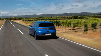 Ein blauer VW ID Polo fährt an Weinreben vorbei, von hinten.