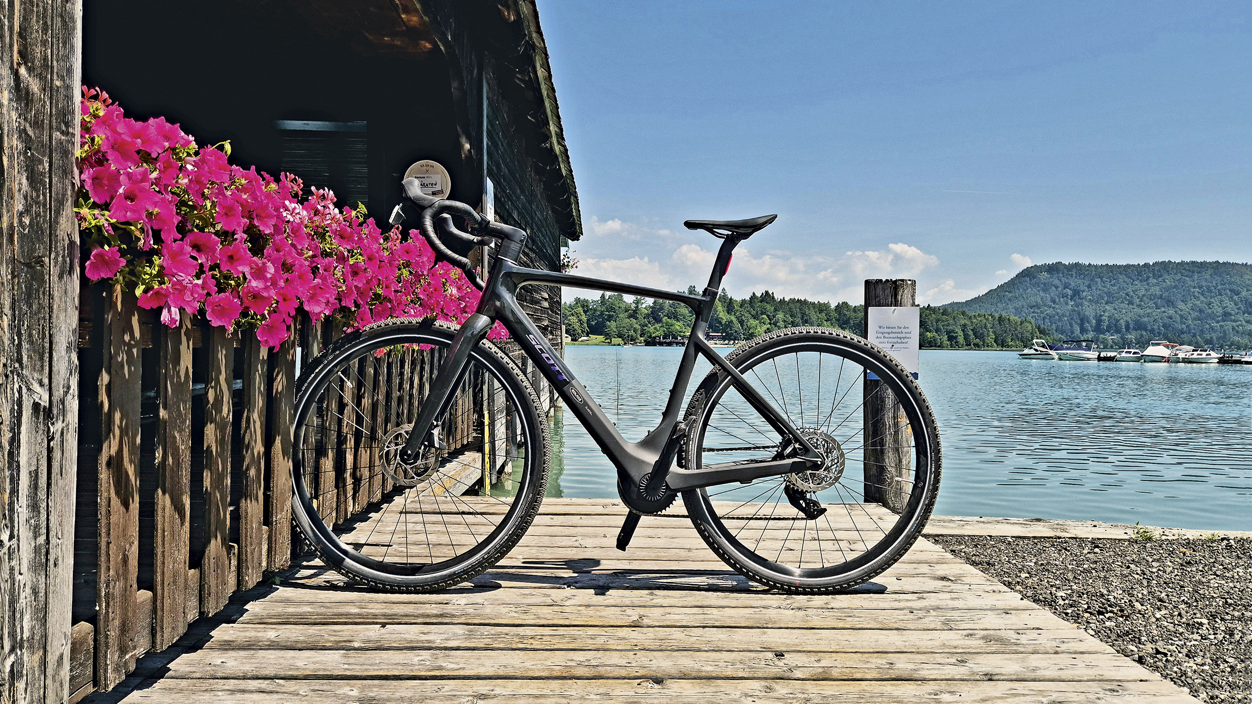 Gravelbike auf Bootsstegg mit türkis-blauem Wasser im Hintergrund