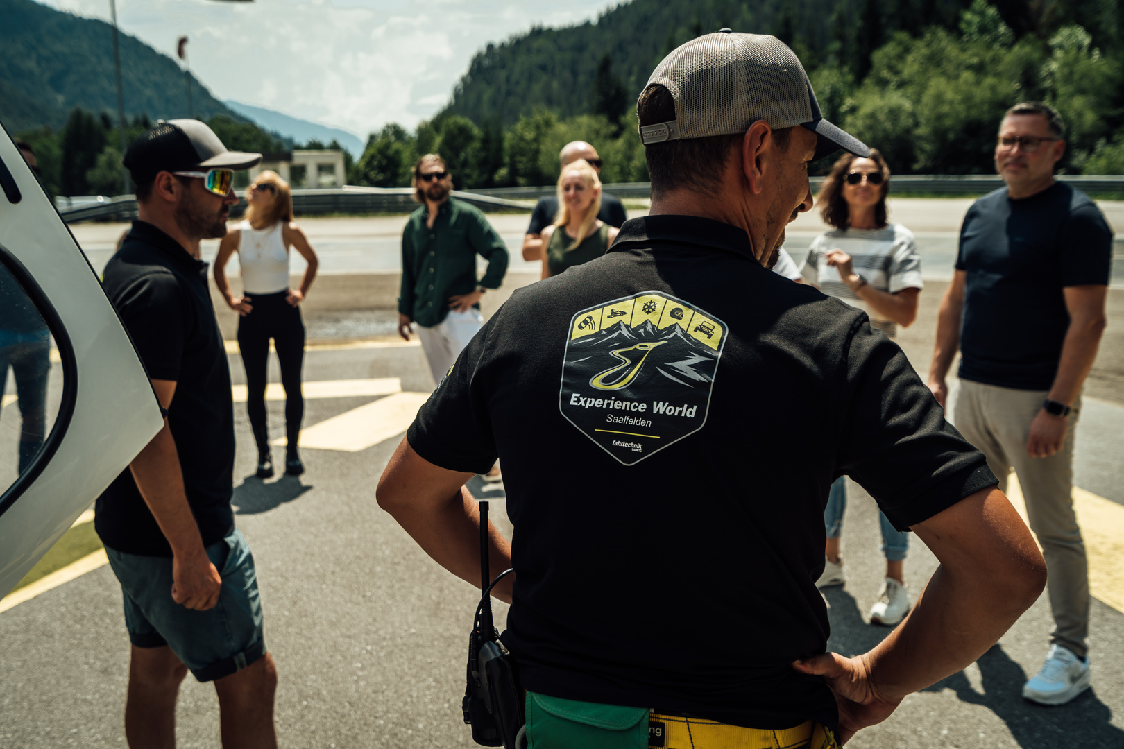 Man sieht einen Instruktor mit dem Logo der Experience World Saalfelden am Rücken, wie er zu einer Gruppe Teilnehmerinnen und Teilnehmern spricht