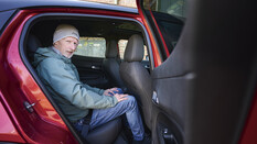 Erwachsener sitzt auf der Rückbank des Alfa Romeo Junior und zeigt dabei die knappe Beinfreiheit.