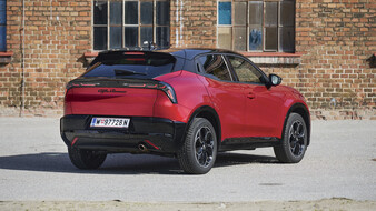 Roter Alfa Romeo Junior Ibrida Q4 von schräg hinten vor einer Backsteinfassade.
