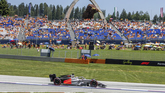 Audi-Formel-1-Rennwagen fährt auf dem Red Bull Ring an einer Lenovo-Werbebande und einer Tribüne vorbei.