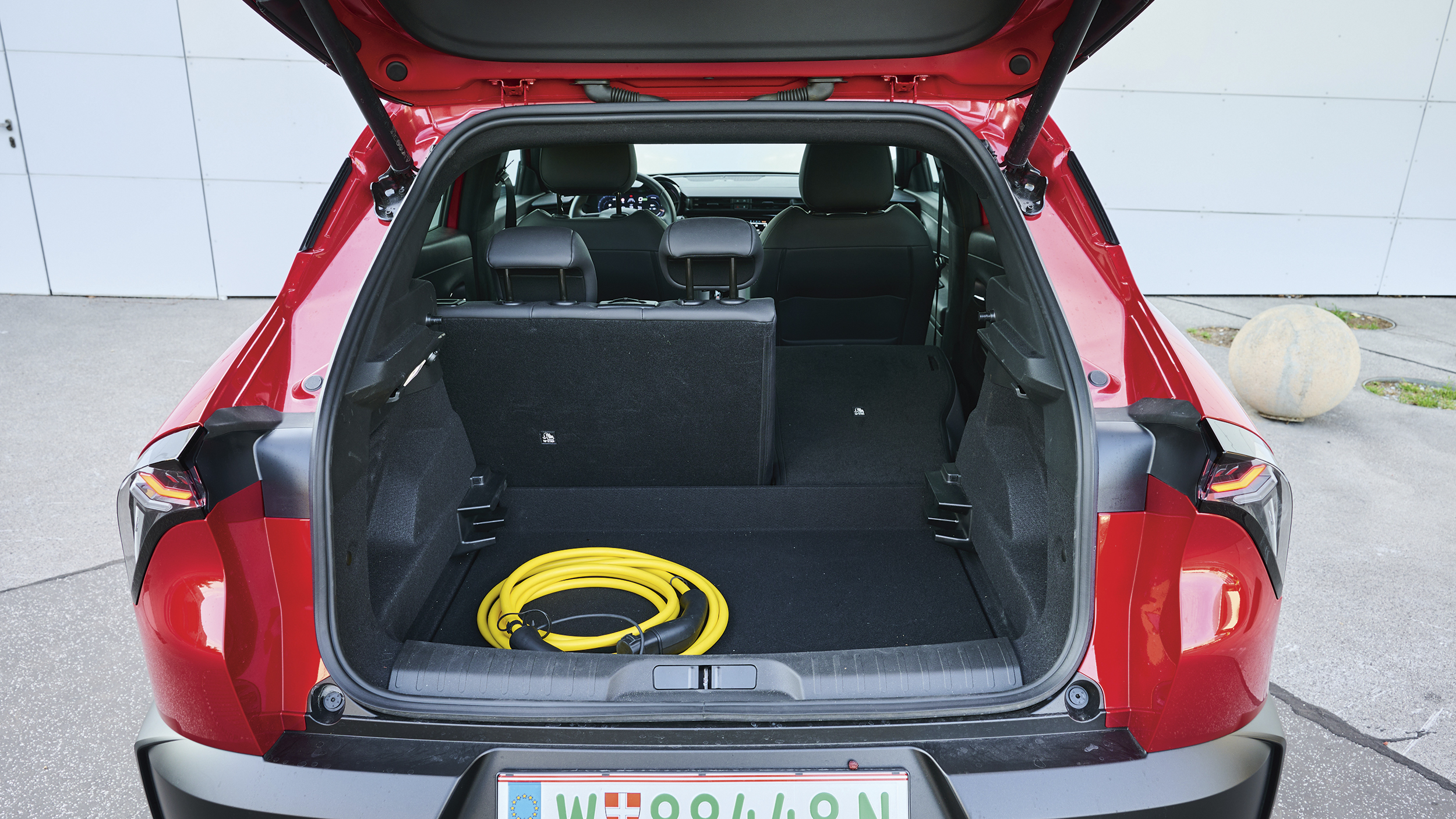 Offener Kofferraum des Alfa Romeo Junior Elettrica mit gelbem Ladekabel.