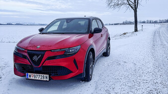 Roter Alfa Romeo Junior im Winter auf verschneiter Landstraße.