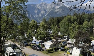 Man sieht auf den Bild einen Campingplatz inmitten der Natur mit Bergen im Hintergrund.