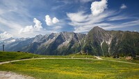Das Bild zeigt eine grüne Wiese und eine Bergkette.
