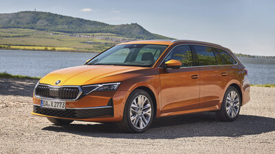 Orangefarbener Škoda Octavia Combi, Kombi in Halbfrontansicht von links schräg vorn, auf einem Schotterplatz an einem See; dahinter Weinberge und ein Hügel.