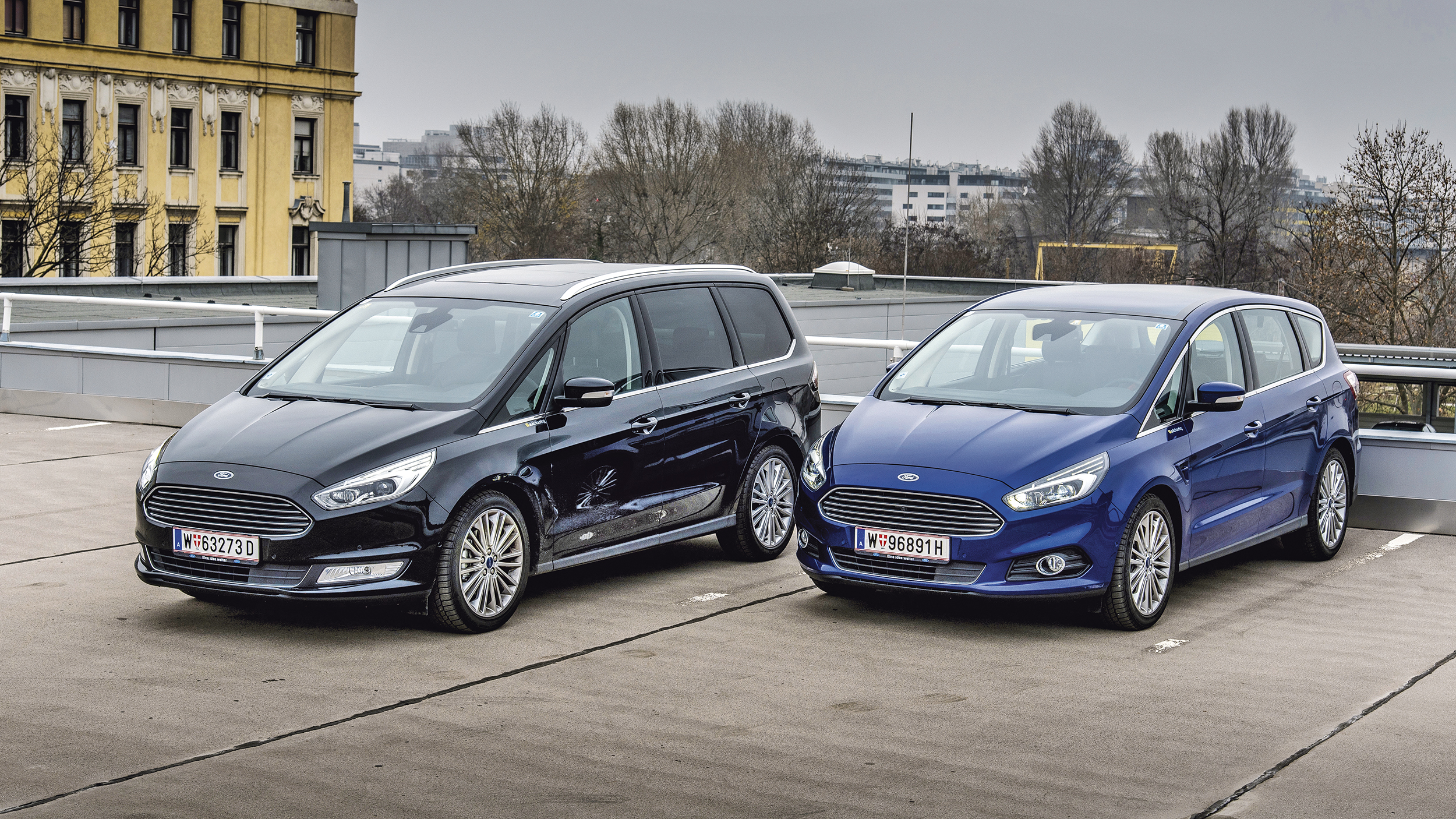 Ein schwarzer Ford Galaxy steht neben einem blauen Ford S-Max.