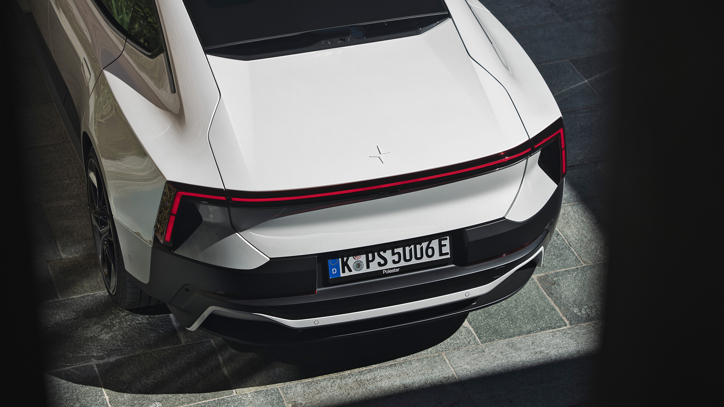 Heckansicht eines weißen Polestar 5 Performance mit durchgehendem roten Leuchtenband und deutschem Kennzeichen.