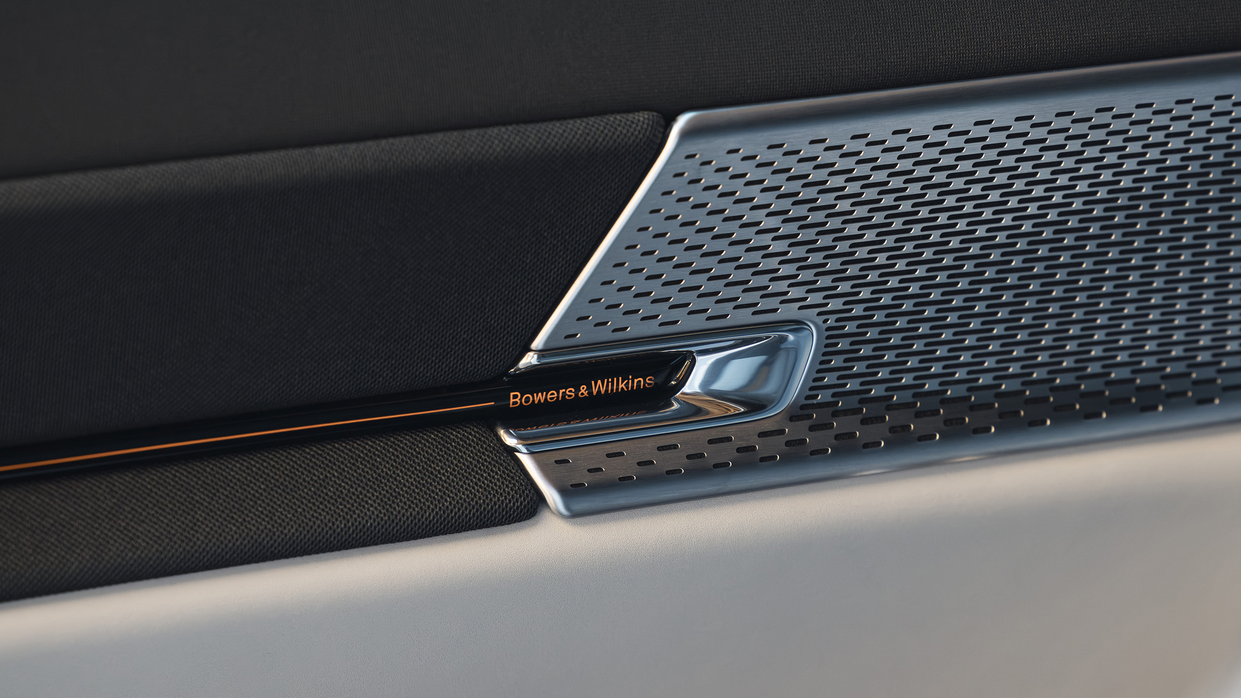 Nahaufnahme eines perforierten Lautsprechergitters im Innenraum mit der Aufschrift „Bowers & Wilkins“.