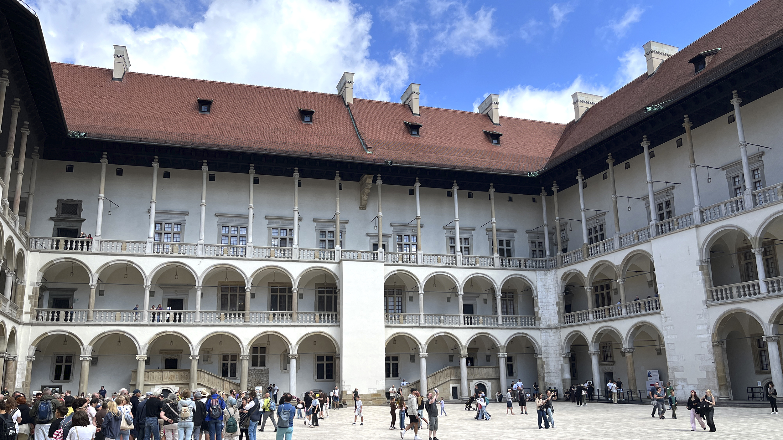 Menschen spazieren vorm Wawel Schloss. 