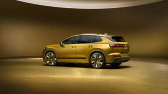 Goldgelber Volkswagen ID. Tiguan in Heckansicht von schräg links in einem gelb beleuchteten Studio.