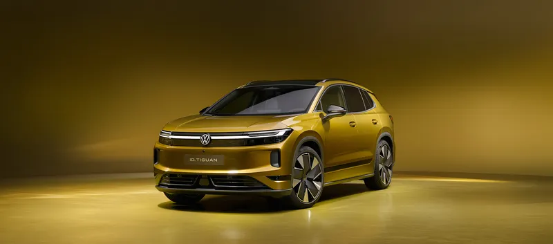 Goldgelber Volkswagen ID. Tiguan in Frontansicht von schräg links in einem gelb beleuchteten Studio.