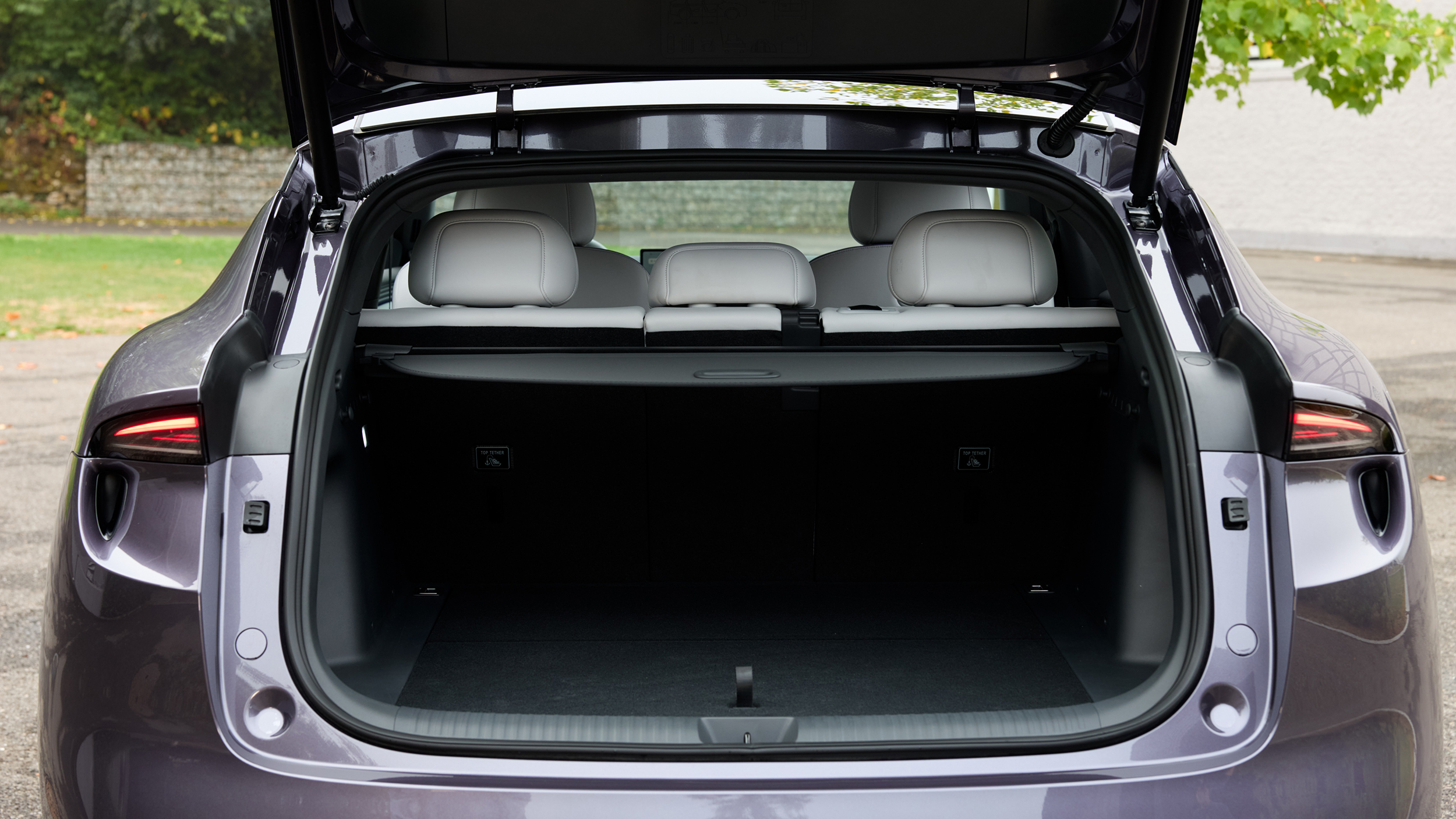 Geöffnete Heckklappe eines violetten SUV mit Blick auf den leeren, schwarz ausgekleideten Kofferraum, die Gepäckraumabdeckung und die aufrechten Rücksitzlehnen.