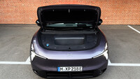 Frontansicht eines violetten SUV mit geöffneter Motorhaube und schwarzer Abdeckung mit mittigem Staufach vor einer Ziegelwand.