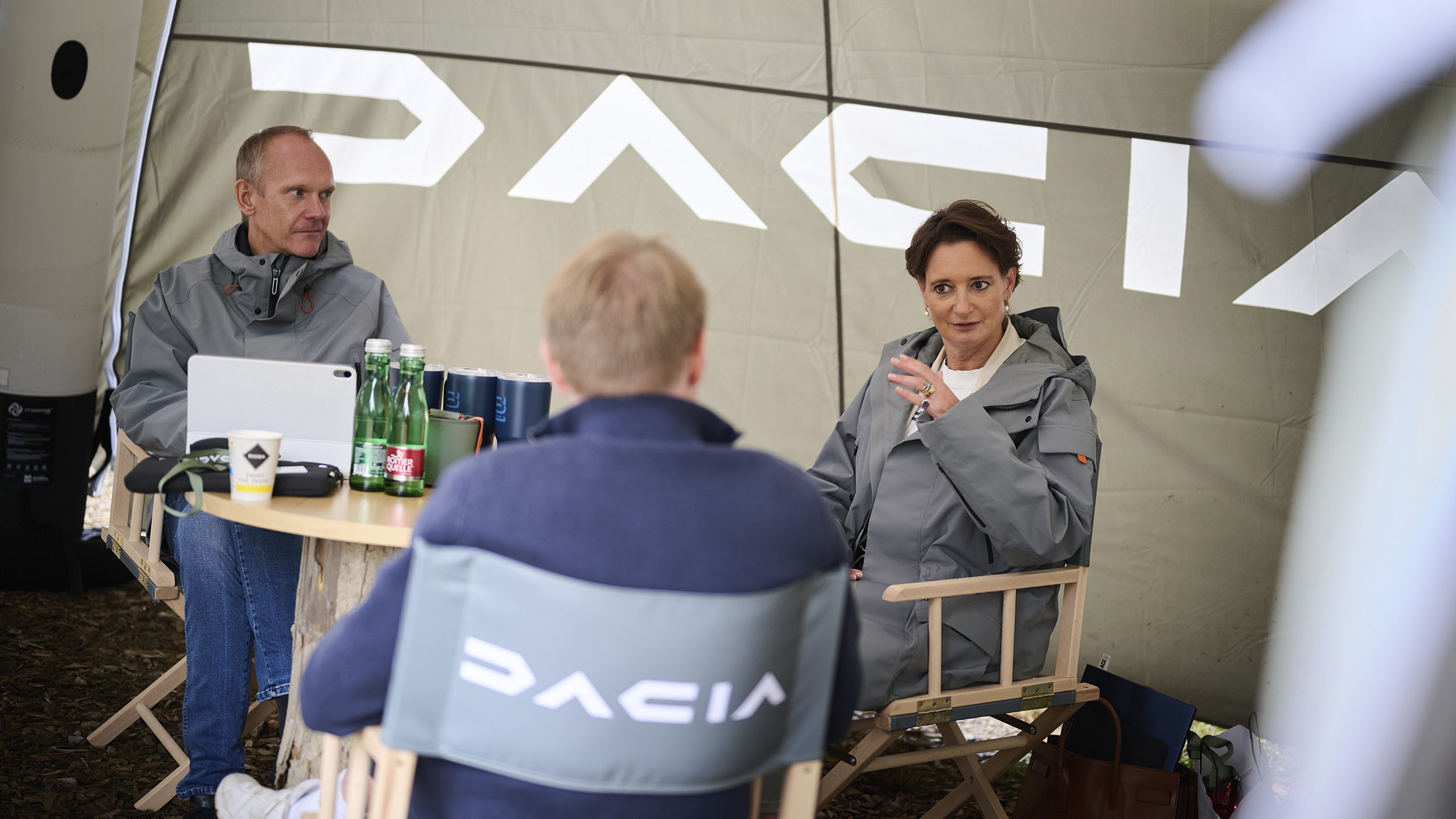 Dacia-CEO Katrin Adt sitzt in einem Zelt und spricht mit dem Renault Österreich Chef und einem Journalisten.