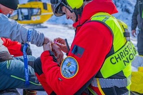 Ein Notarzt verabreicht auf eine Skipiste einem Patienten eine Infusion