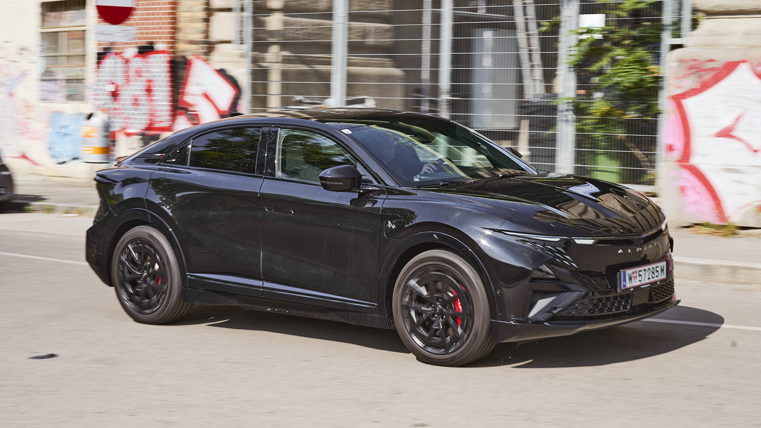 Eine schwarze Alpine A390 GT fährt auf einer Straße in der Stadt.