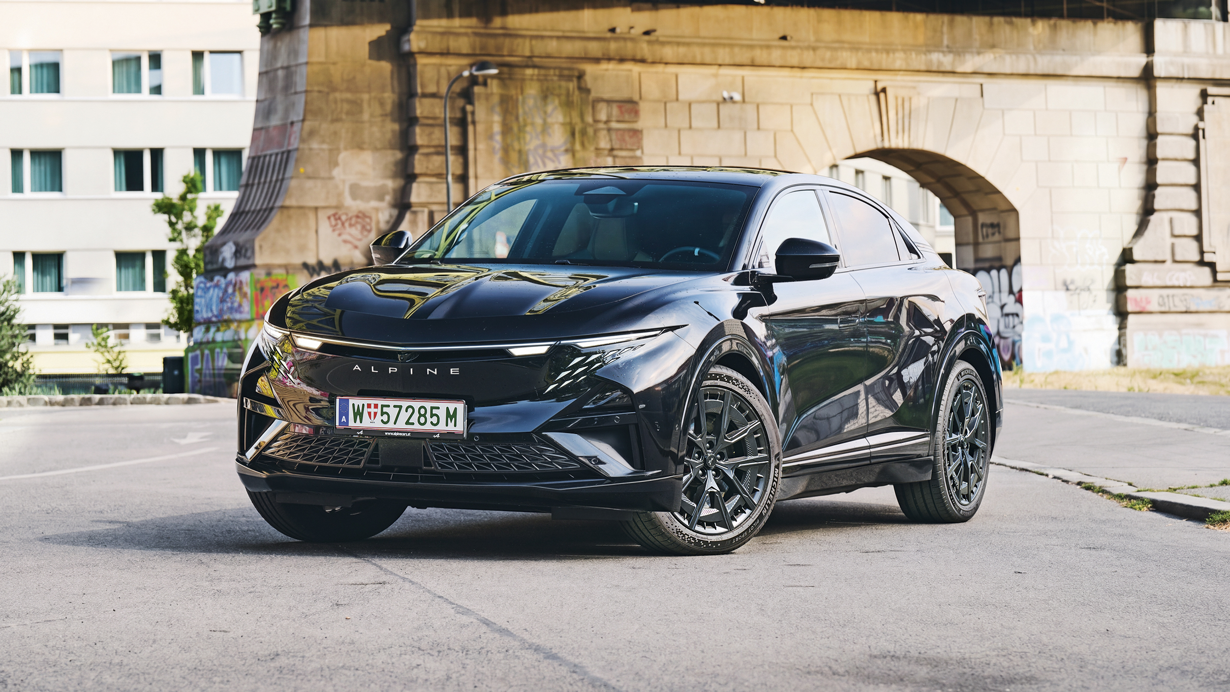 Front einer schwarzen Alpine A390 GT, die unter einer Brücke in der Stadt steht.