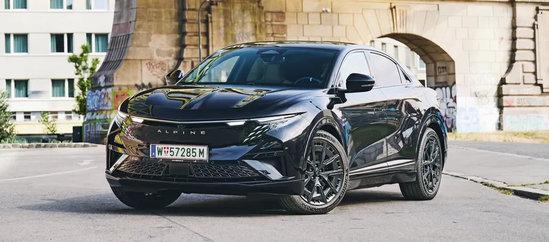 Front einer schwarzen Alpine A390 GT, die unter einer Brücke in der Stadt steht.