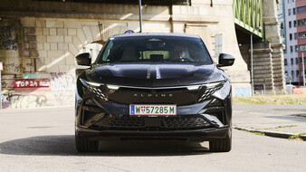Front einer schwarzen Alpine A390 GT, die unter einer Brücke in der Stadt steht.