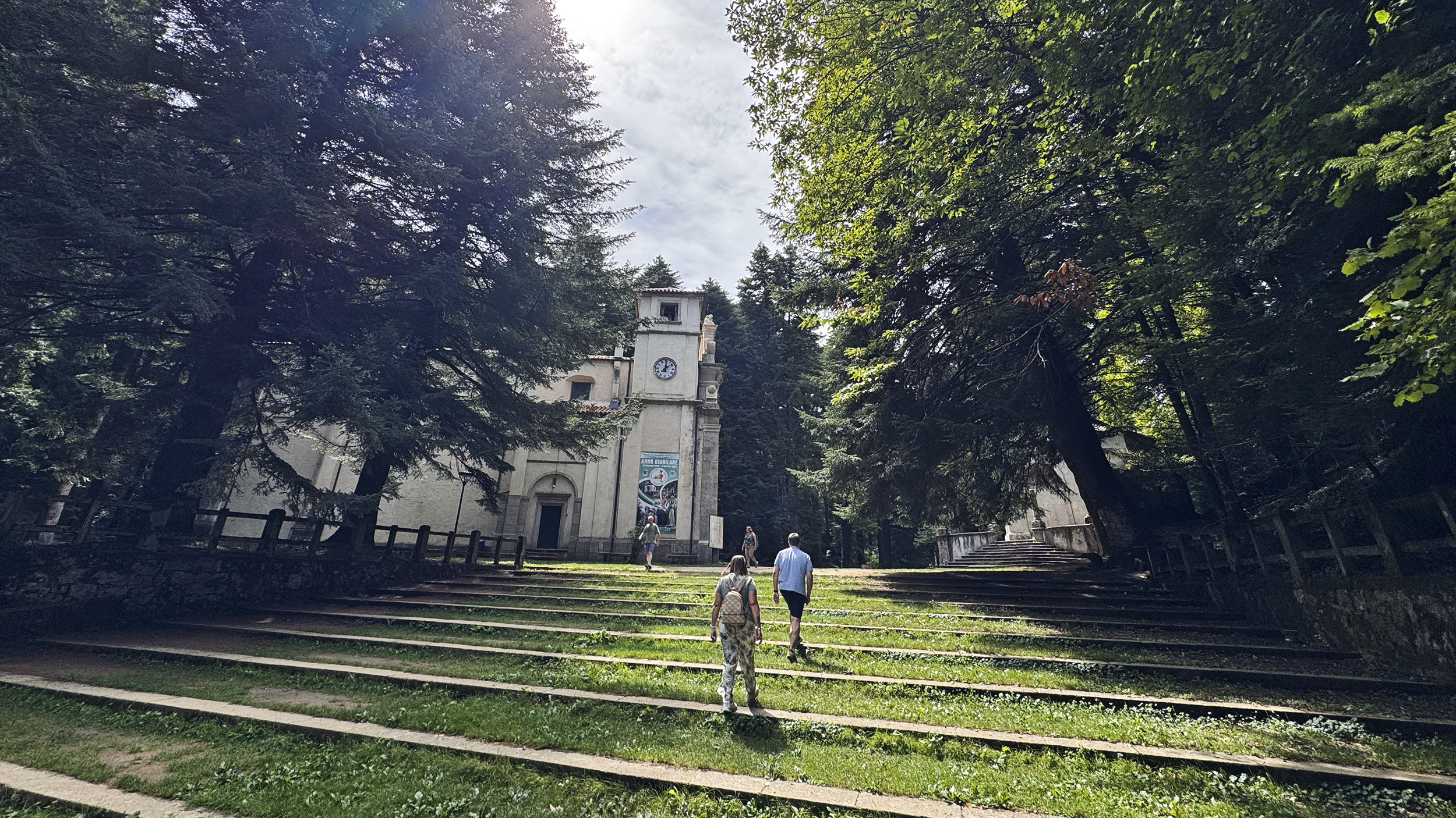 Menschen gehen die Treppen hinauf zu einer Kirche im Wald.