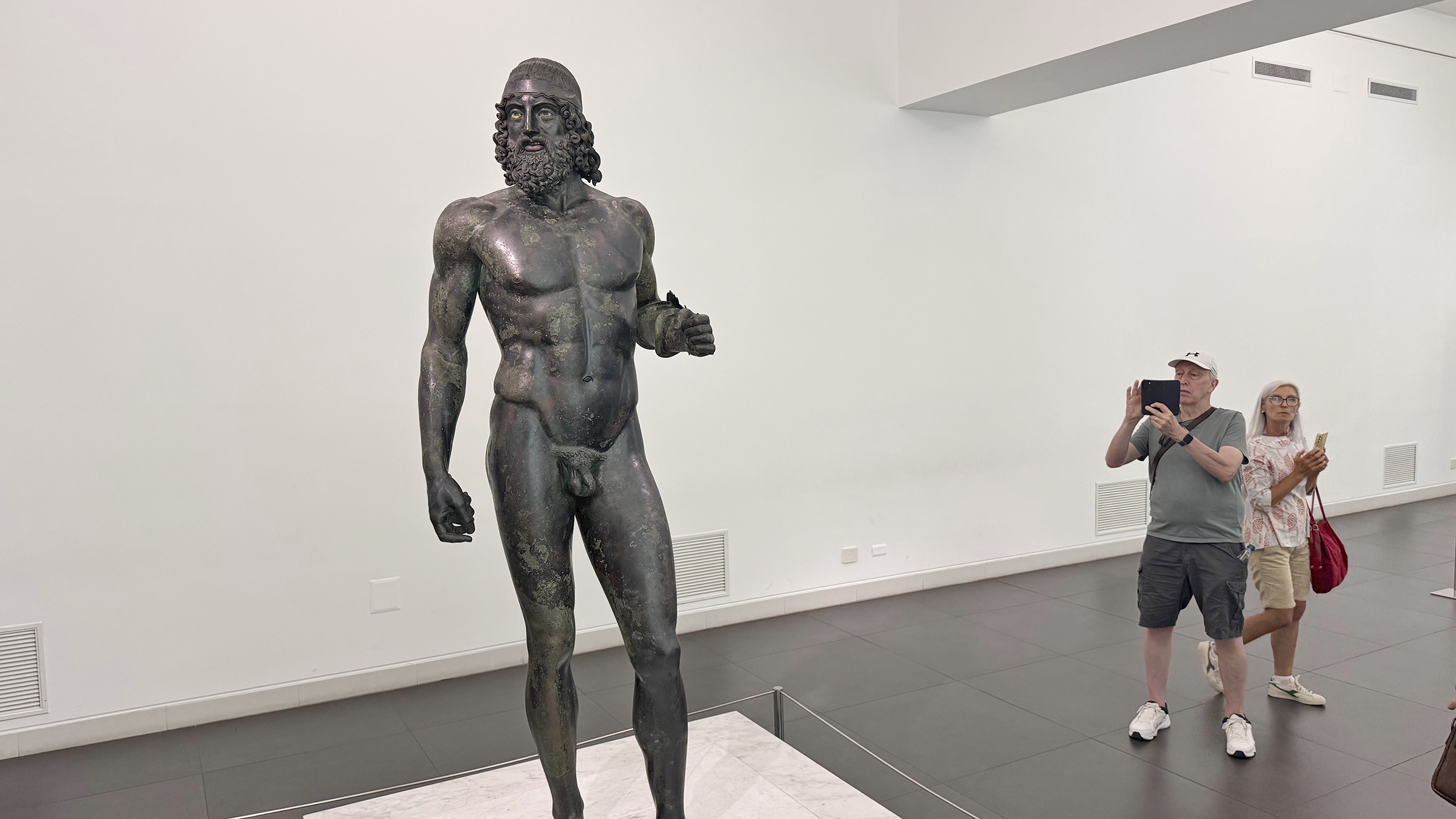 eine Bronzestatue im Museum. Menschen fotografieren sie.