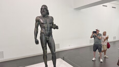eine Bronzestatue im Museum. Menschen fotografieren sie.
