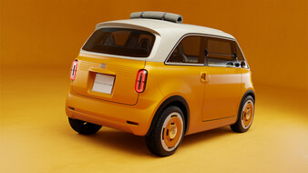 Orangefarbener Fiat Multiplina schräg von hinten mit weißem Dach, hochkant angeordneten Rückleuchten und einer festgeschnallten grauen Rolle auf dem Dach.