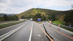 Dreistreifige Autobahnbaustelle mit einer Betonleitwand und verengten Fahrstreifen.