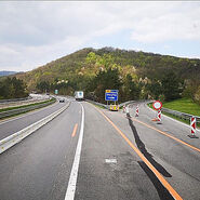 Dreistreifige Autobahnbaustelle mit einer Betonleitwand und verengten Fahrstreifen.