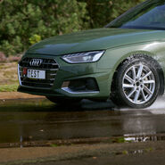 Ein Schmuckbild zum ÖAMTC-Sommerreifentest 2026: Ein grünes Auto fährt über eine nasse Straße. Der Fokus der Kamera liegt auf dem linken Vorderreifen. Auf dem Kennzeichen des Autos steht das Wort TEST.