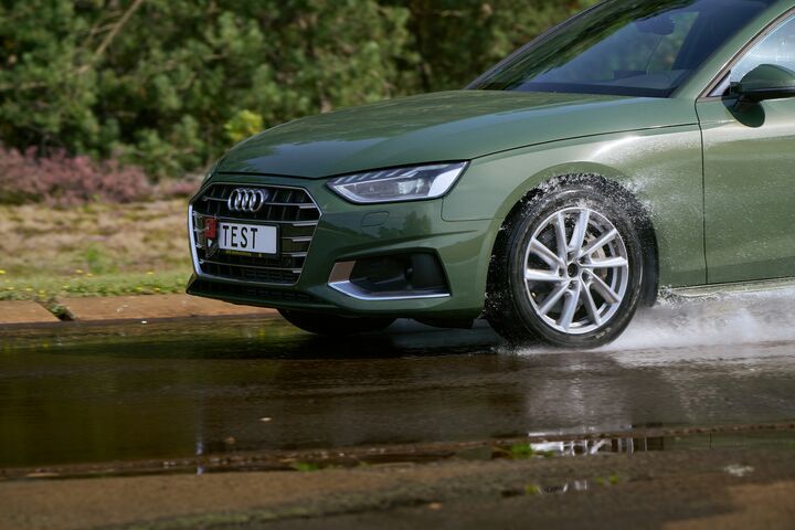 Ein Schmuckbild zum ÖAMTC-Sommerreifentest 2026: Ein grünes Auto fährt über eine nasse Straße. Der Fokus der Kamera liegt auf dem linken Vorderreifen. Auf dem Kennzeichen des Autos steht das Wort TEST.